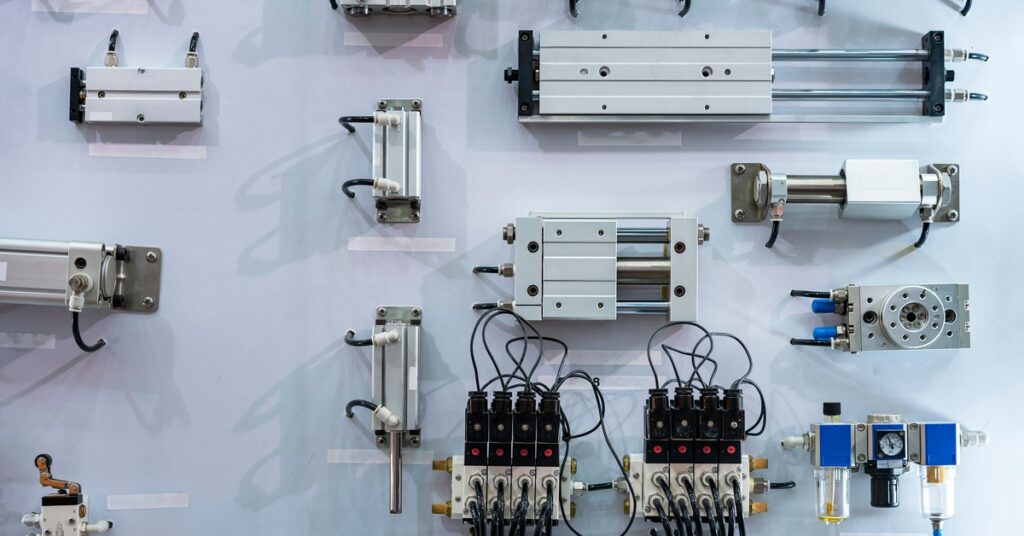 A variety of pneumatic actuators, solenoid valves, and cylinders mounted on a display wall with visible ports and cables.