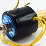 An industrial solenoid valve with yellow wires and a black cylindrical housing positioned against a plain white background.