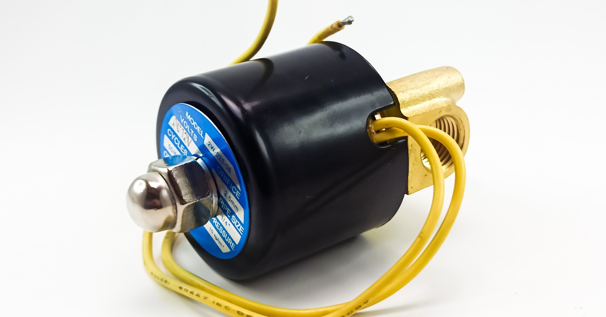 An industrial solenoid valve with yellow wires and a black cylindrical housing positioned against a plain white background.