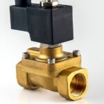 A single solenoid valve sits on a white background. The valve has a brass bottom with a black top.