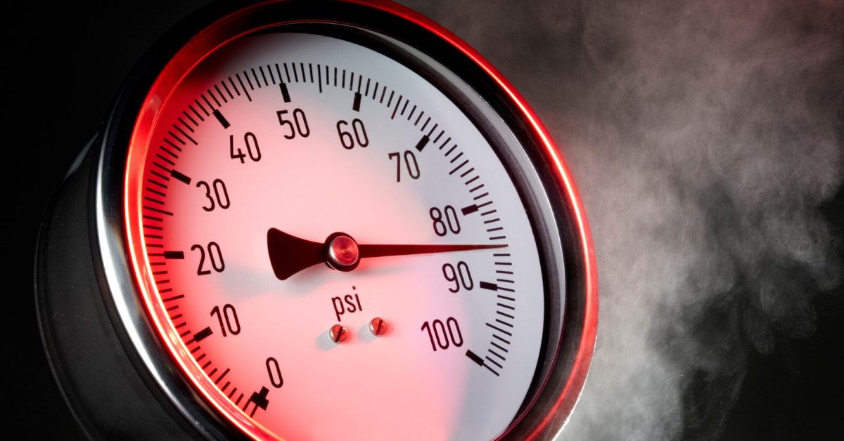 A close-up view shows a dimly lit pressure gauge with smoke coming from behind it. The gauge lists numbers 1-100 in tens.