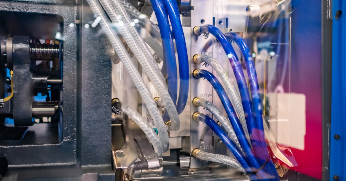 An encapsulated molding blue and silver molding machine features blue and clear tubes coming out of the sides of it.