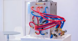 A metal molding machine sits in an industrial setting with several blue and red tubes coming out of the sides.