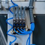 An industrial system features solenoid valves and has gray ribbed tubing coming out the top and blue tubing from the side.