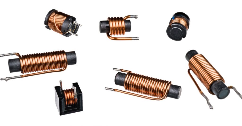 A set of seven copper solenoid coils sit on a white background. The coils are on plastic, black cylinders.