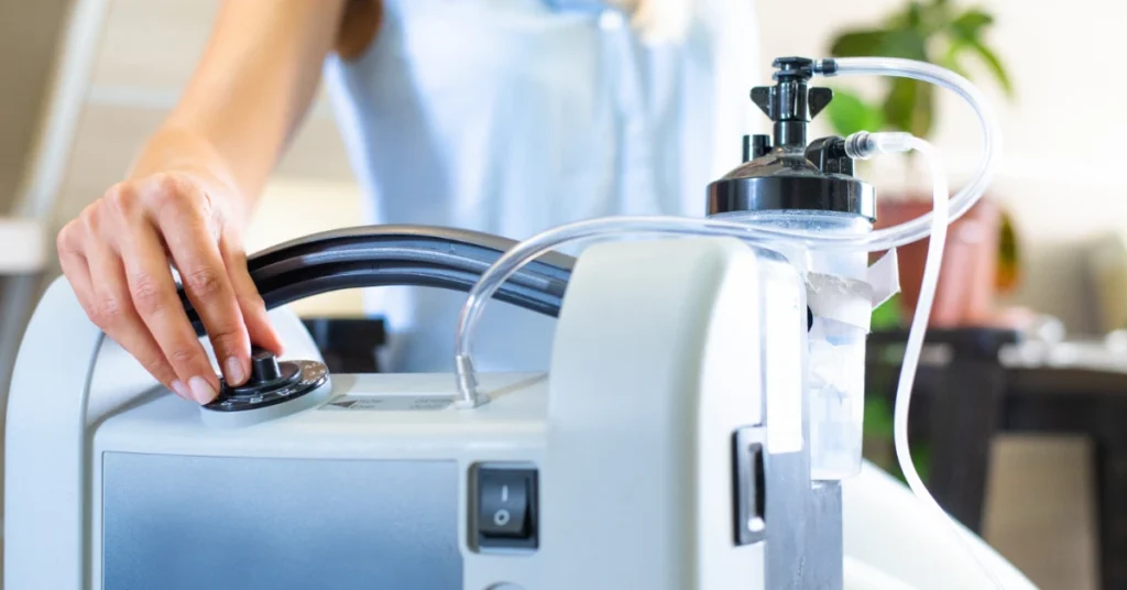 A close-up view shows a person adjusting the dial on a medical device. The device has skinny clear tubes coming out the top.