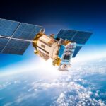 A satellite is floating around in space. Behind the satellite you can see the clouds from Earth's atmosphere.