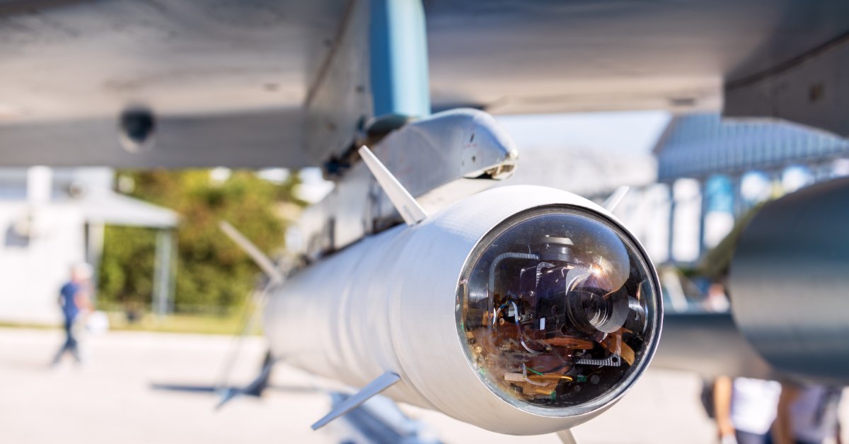 A close-up view shows the end of a missile that's attached to the wing of an aircraft. The end is clear.