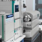 Biotech equipment is sitting on a table in a modern laboratory next to another table that has a desktop computer.