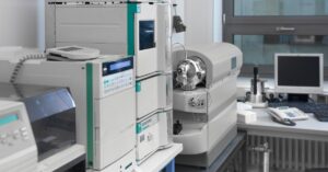 Biotech equipment is sitting on a table in a modern laboratory next to another table that has a desktop computer.