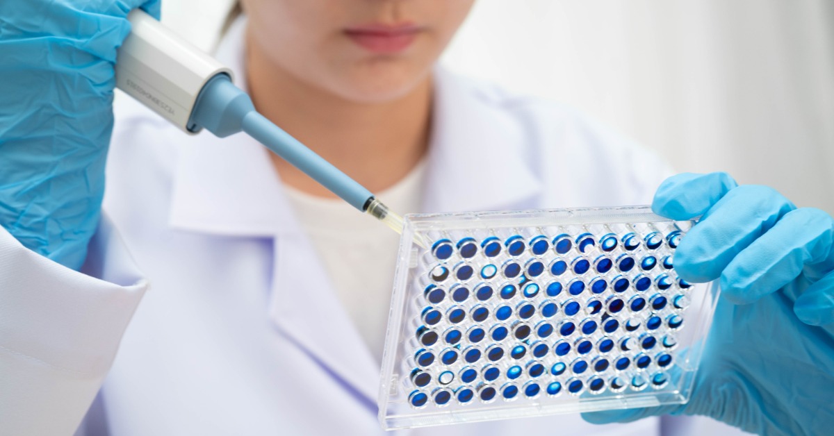 A close-up view shows a female scientist using a tool to place cell cultures on a sample microplate.