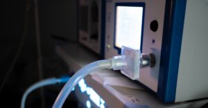 A close-up view shows a laparoscopic insufflator lit up with a clear plastic hose coming out the front.